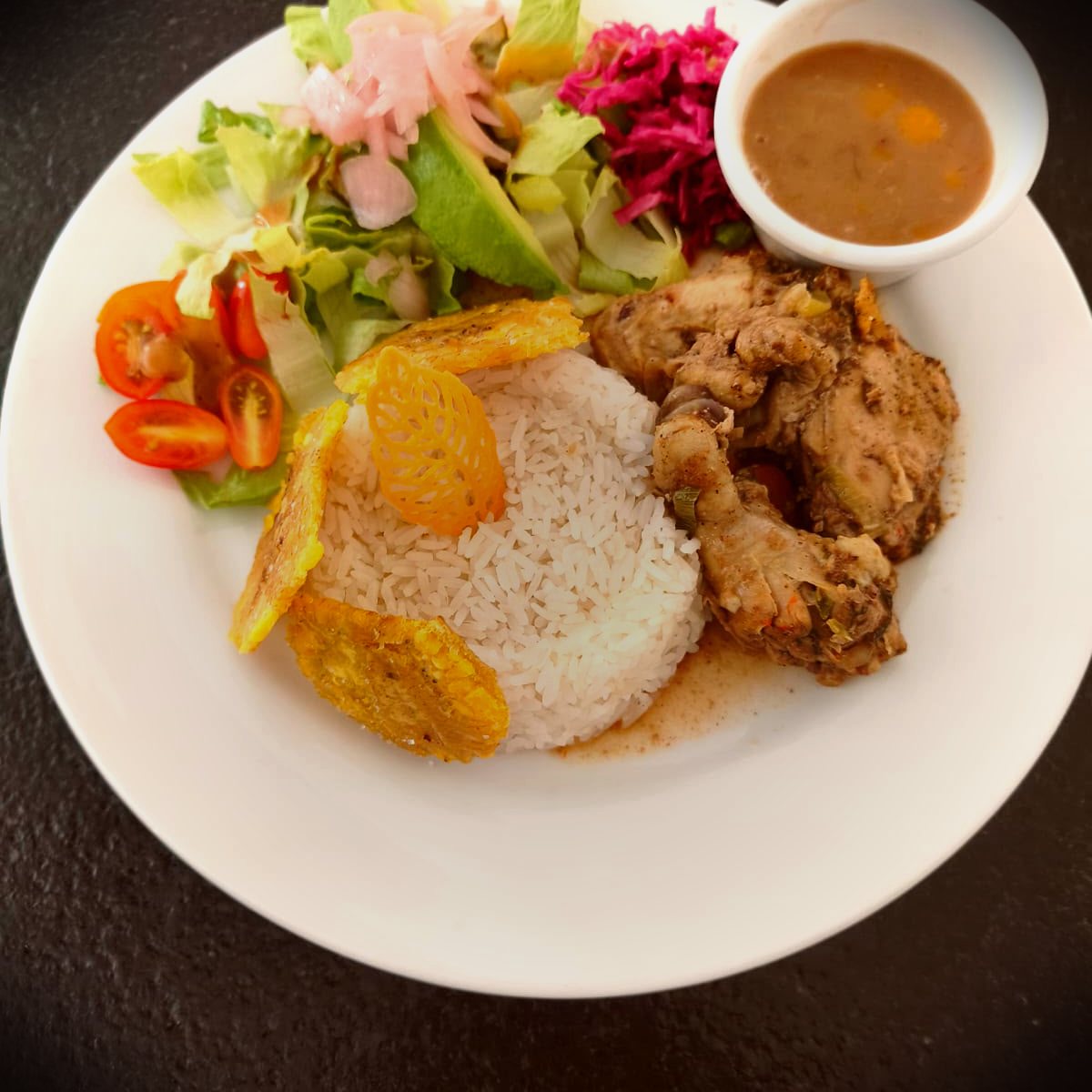 Dominican-style stewed chicken with rice, tostones, and salad