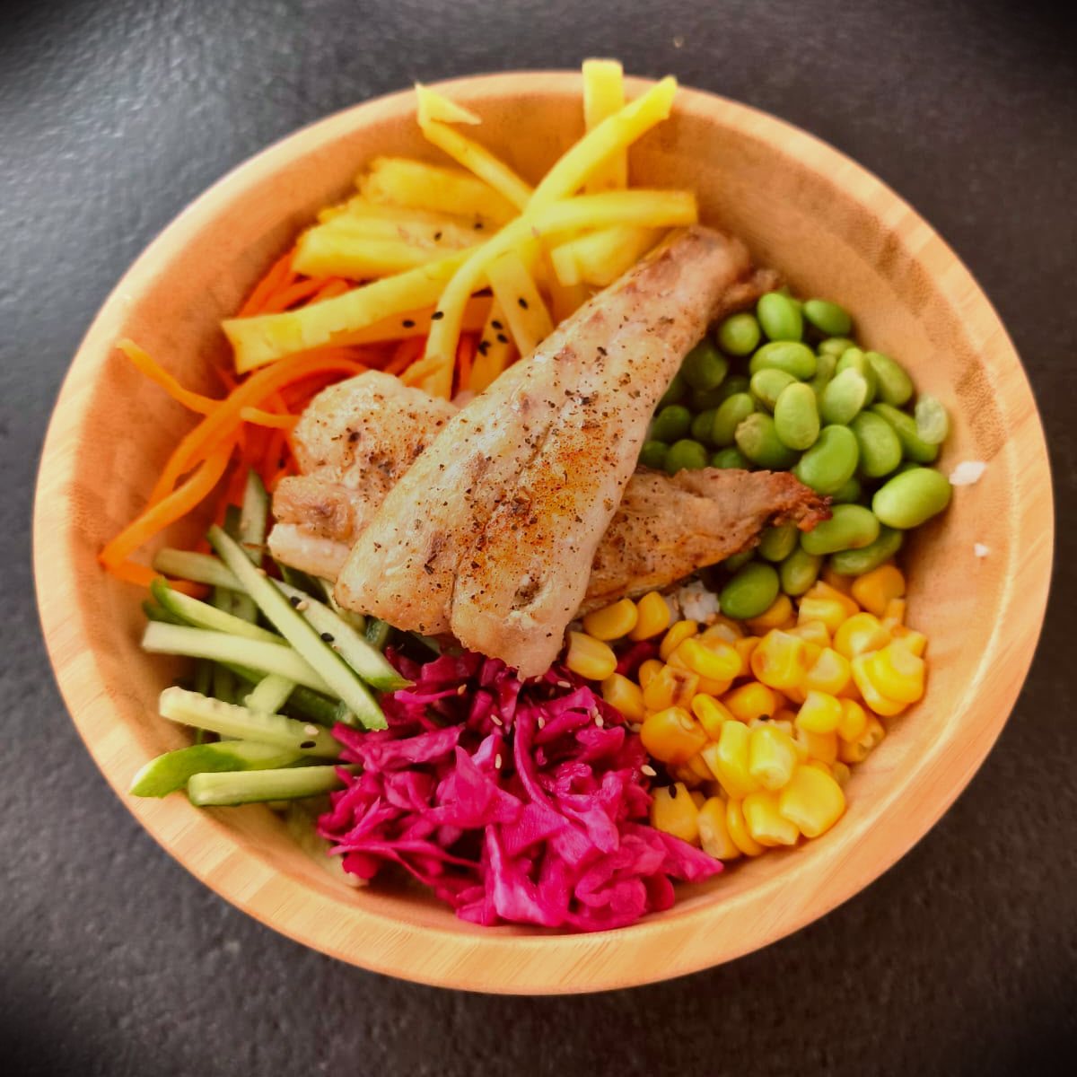 Rainbow poke bowl with pineapple, edamame, pickled cabbage, and seared fish